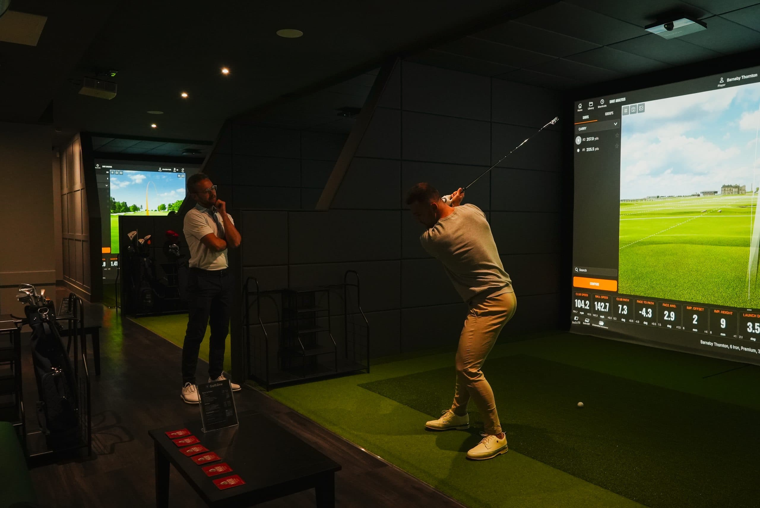 A golfer taking a lesson in a Trackman bay